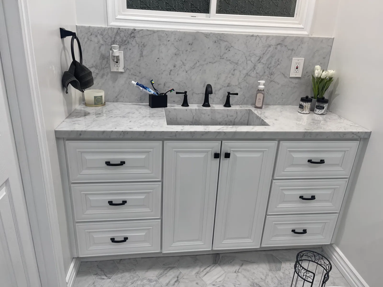 Remodeled bathroom with a white vanity, a stone counter and black fixtures